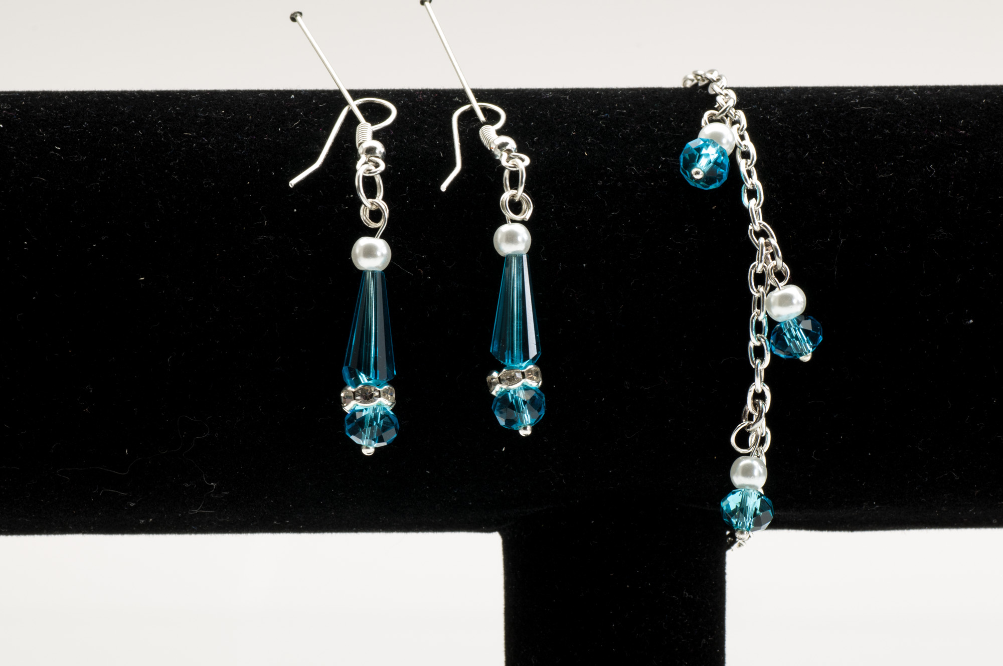 Havsgröna kristalldroppar med pärla och glittrande mellandel i örhängen, samt kedjearmband med små dinglande kristaller.