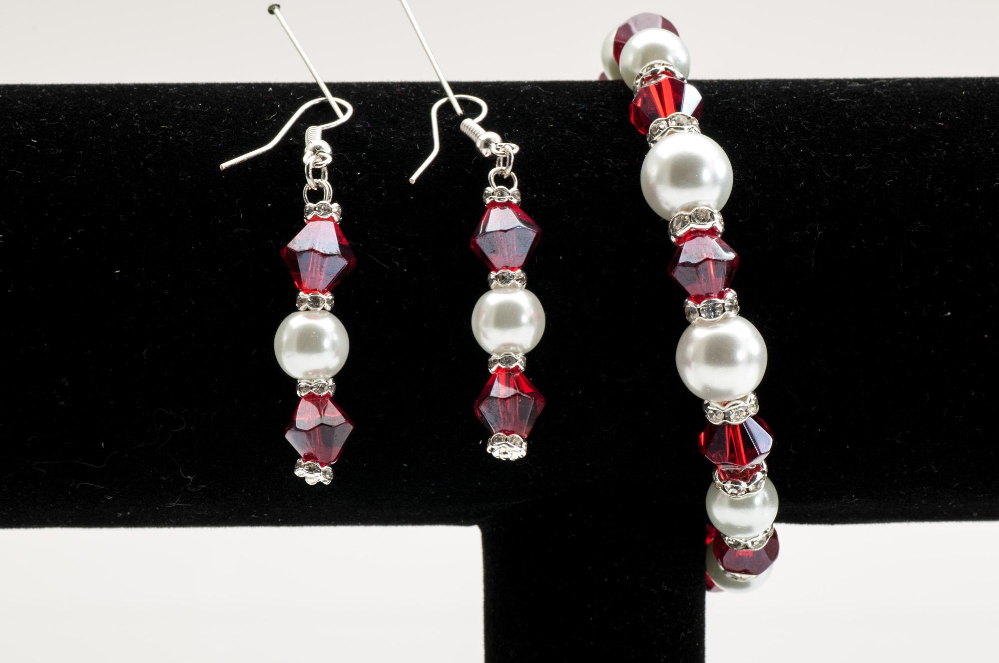 Rött och pärlvitt smyckeset: hängörhängen med facetterade röda kristaller, pärlvita glaspärlor och glittrande mellandelar. Matchande armband.