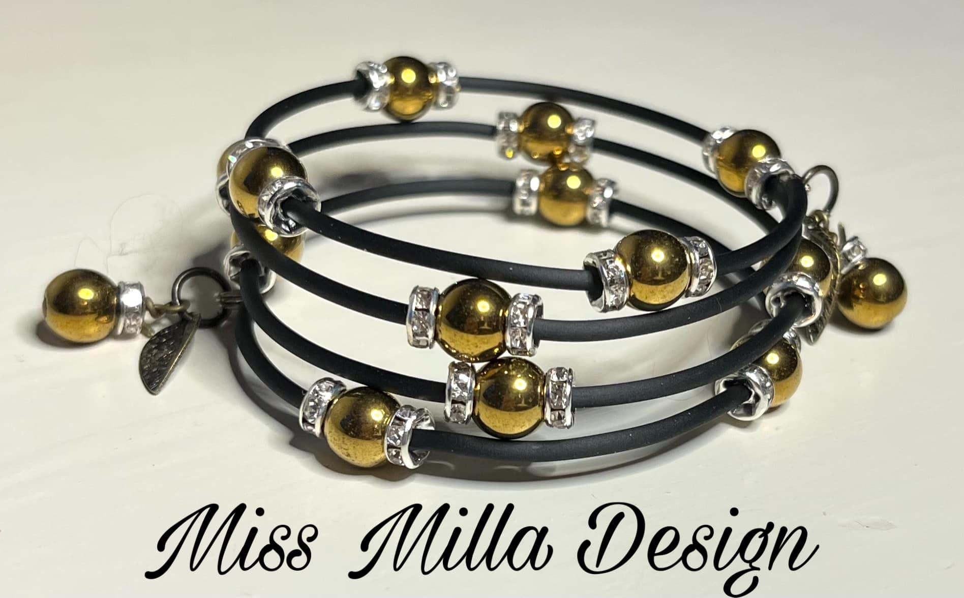 Fler-varvsarmband i svart tub/minneswire med guldfärgade metallpärlor och strassrondeller i silver.